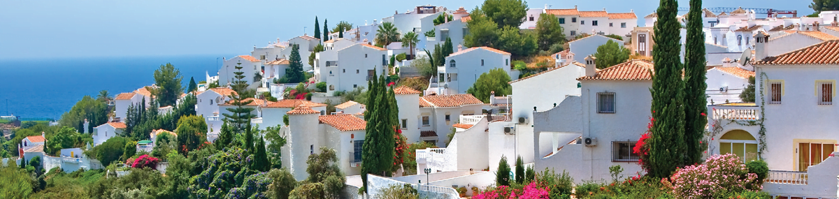 White residential buildings in Spain on a hill top overlooking the ocean.